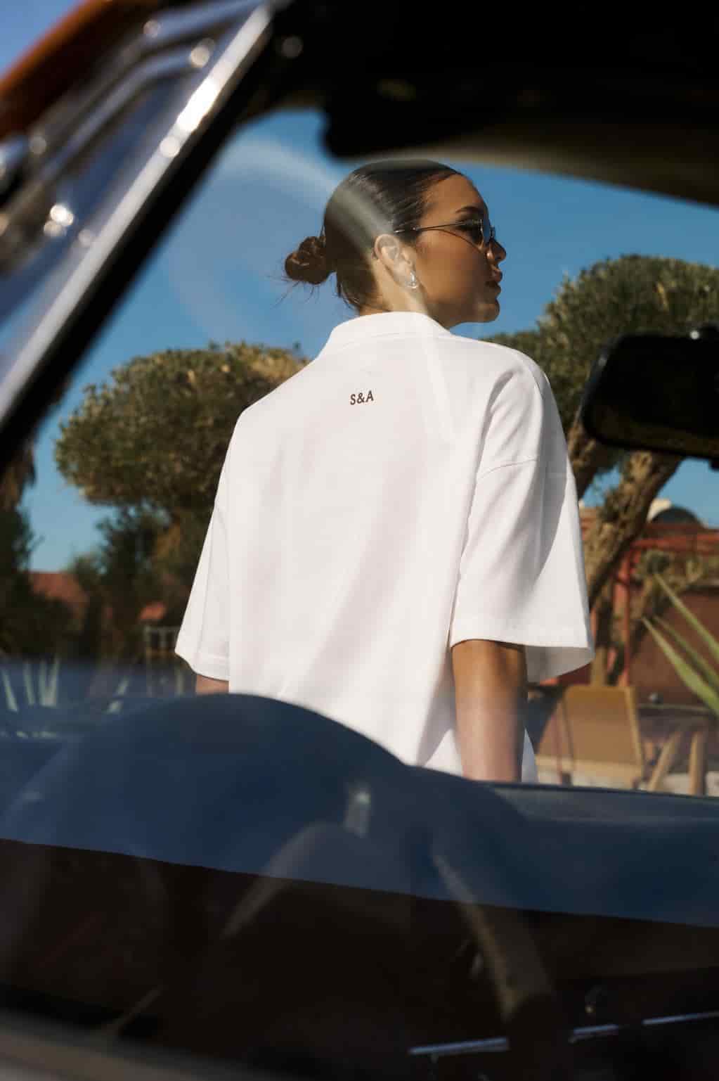 Woman wearing a white S&A Collection oversized T-shirt beside a car