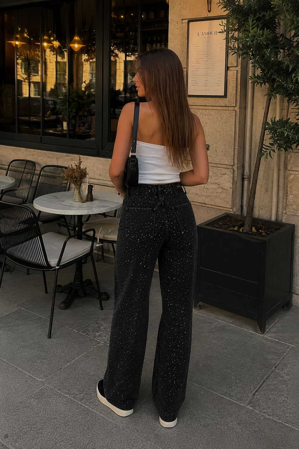 Female model wearing black embellished wide-leg pants with a white strapless top