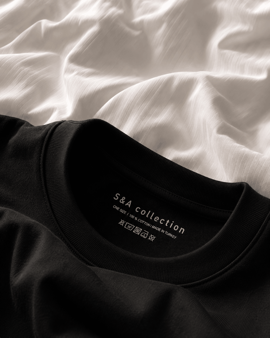 Close-up of the black oversized T-shirt showing the ribbed collar, inner S&A Collection label and cotton fabric texture