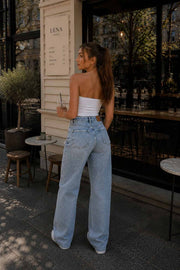 Female model wearing blue embellished wide-leg jeans with a white strapless top