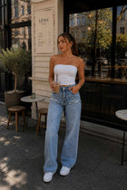 Female model wearing blue embellished wide-leg jeans with a white strapless top