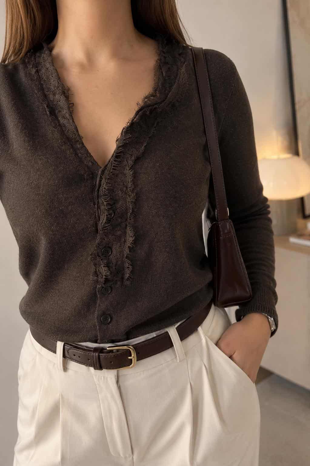 Close-up of a brown lace-trim button cardigan styled with cream tailored trousers