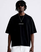 Male model wearing the black CONFIDENT oversized T-shirt with white trousers