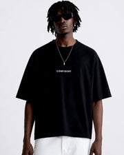 Male model wearing the black CONFIDENT oversized T-shirt with white trousers