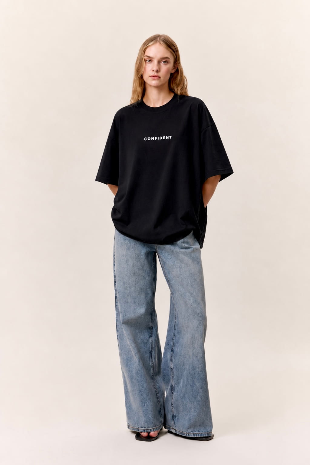 Female model wearing the black CONFIDENT oversized T-shirt with wide-leg jeans