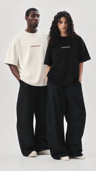 Male and female models wearing black and white CONFIDENT oversized T-shirts in a studio setting