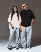 Female and male models wearing black and white CONFIDENT oversized T-shirts with grey sweatpants