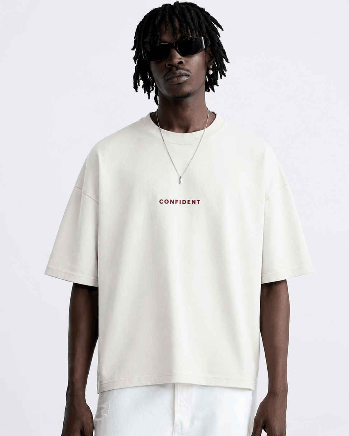 Male model wearing the white CONFIDENT oversized T-shirt with white trousers