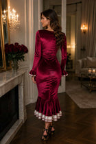Back view of a female model wearing a burgundy Velvet Midi Dress with a fitted silhouette and ruffle hem