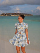 Female model wearing the White And Blue Flowers Dress on a tropical beach