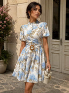 Female model wearing the White And Blue Flowers Dress with a belt and handbag