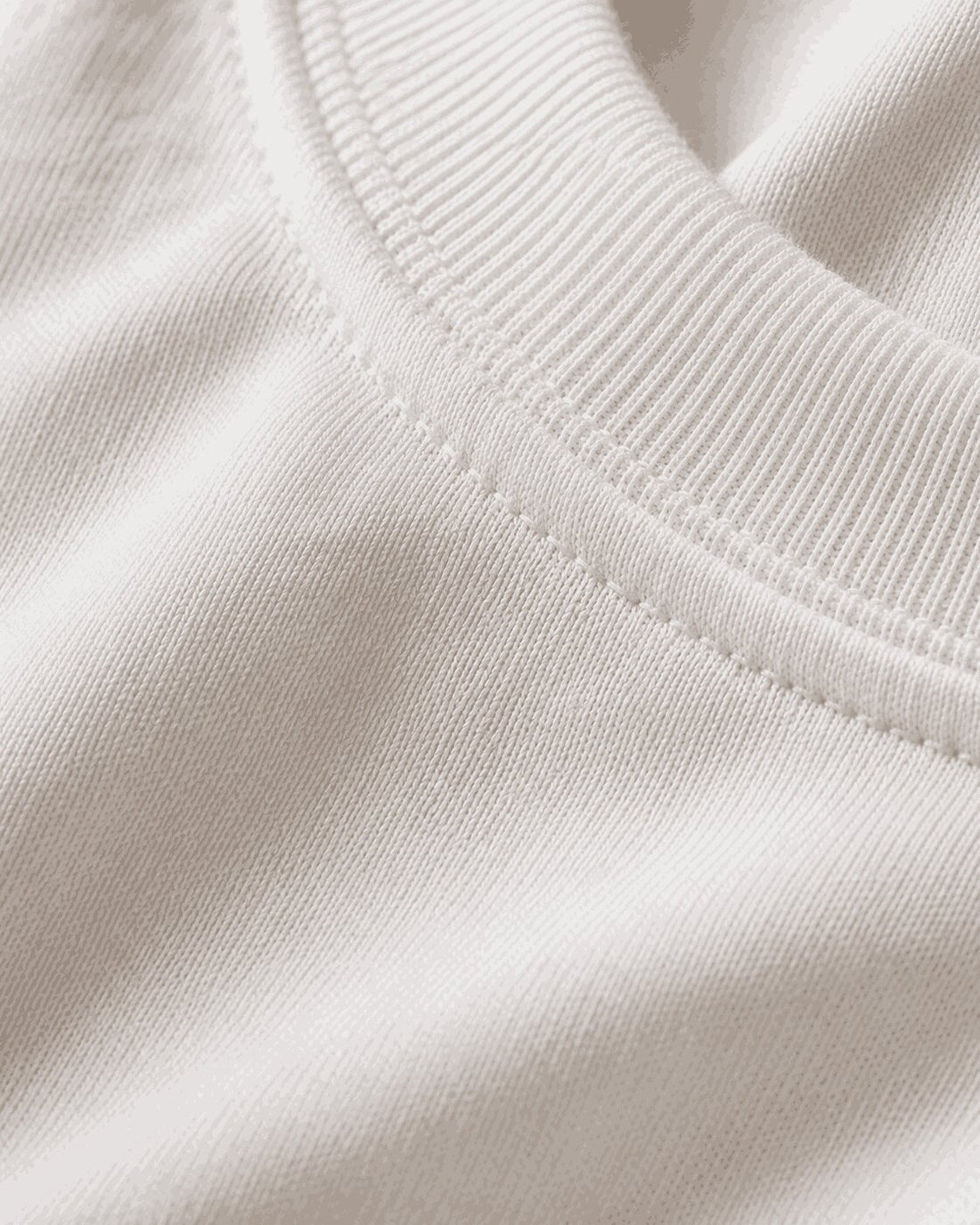 Close-up of the white oversized T-shirt showing the ribbed crew neckline and cotton fabric texture